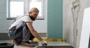 Koliko košta renoviranje vodovodne instalacije u kupatilu? Majstor postavlja pločice tokom renoviranja kupatila